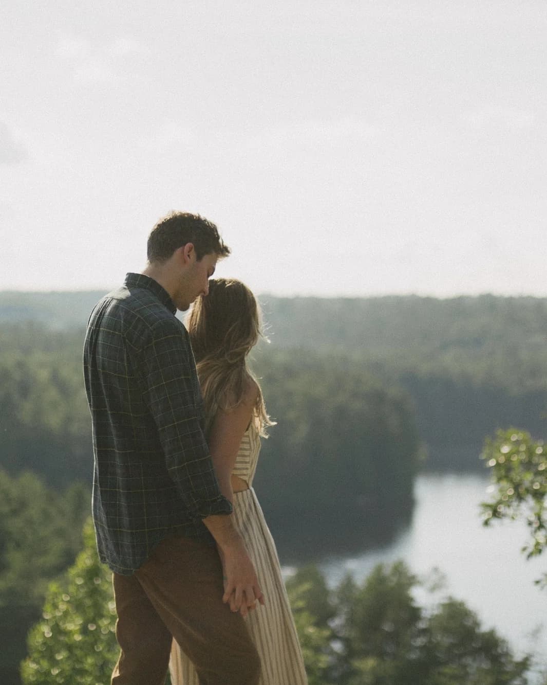 Couple looking over a wooded river overlook.