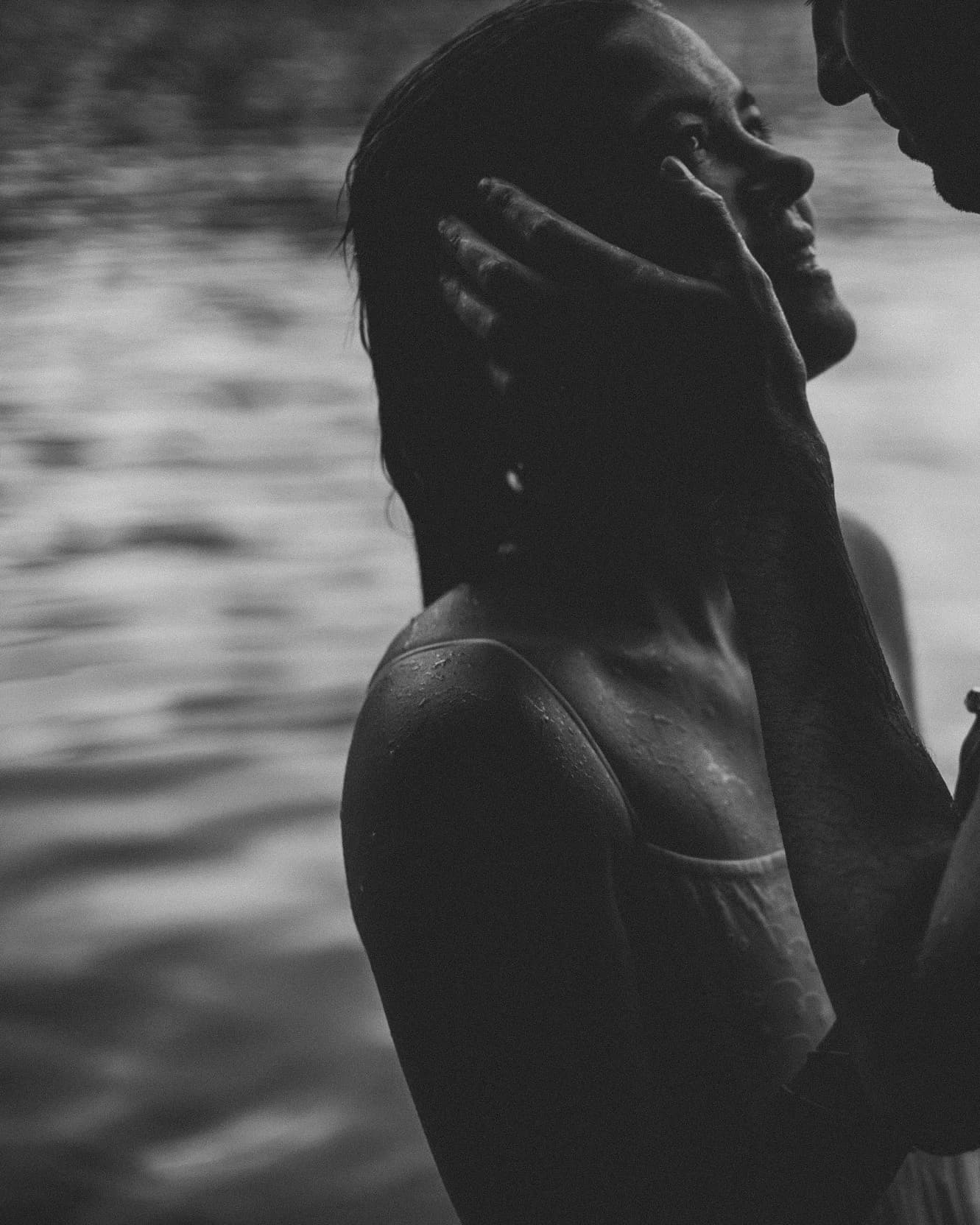 Black and white close portrait of the couple by the water.